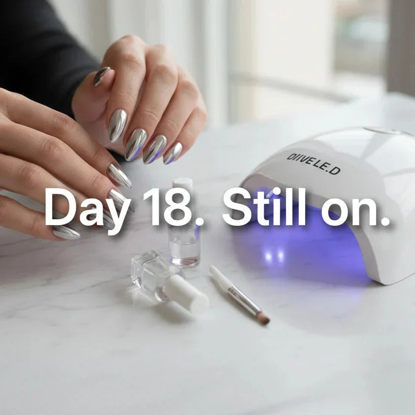 Press-on nails with glossy gel top coat seal on day 18, UV LED lamp and nail products on marble surface