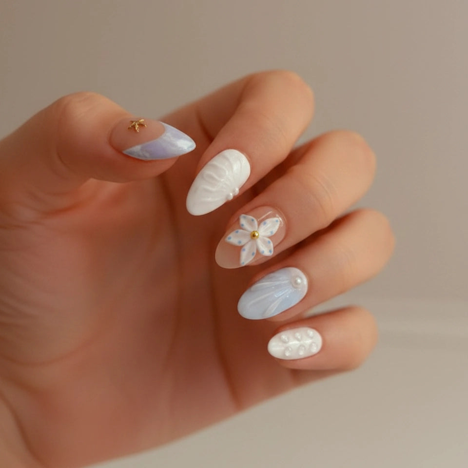 Ocean Bloom Handmade Press-On Nails close-up — short almond shape, nude base with lavender-blue diagonal marble and gold starfish charm on thumb, white 5-petal flower on middle finger, light blue aurora texture on ring finger, pearl dot pinky | MOONLEE