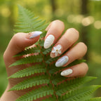 Ocean Bloom Press-On Nails on hand touching green fern leaves in summer forest — short almond nails with 3D starfish charm, white flower, pearl accents, lavender-blue aurora design | MOONLEE