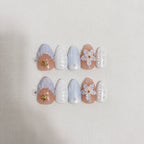 Ocean Bloom  Handmade Press-On Nails flat lay display — 10 pieces in two rows showing left and right hand set, short almond shape with lavender-blue marble, gold starfish charm, white 5-petal flower, pearl dot accents on white linen background | MOONLEE