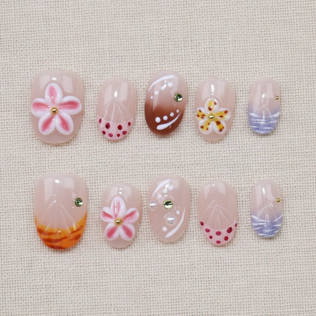 Whispering Sands Handmade Press-On Nails flat lay — 10 pieces in two rows showing full set, short round shape with pink cherry blossom flower, brown gradient pearl dots, yellow starfish charm, burgundy dot clusters, purple-blue watercolor stripes on soft linen textile background | MOONLEE